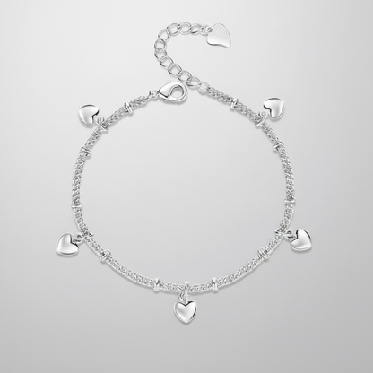 Silver bracelet with heart charms on a light grey background.