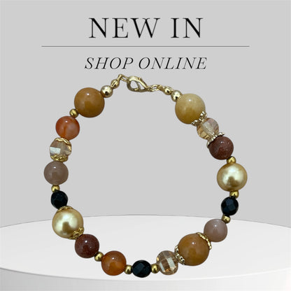 Beaded bracelet with gold accents on a light grey background.