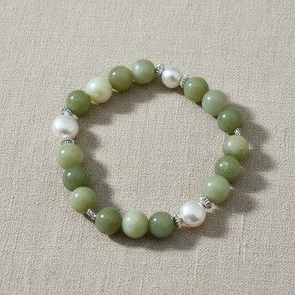 Green beaded bracelet with silver accents on a linen background.