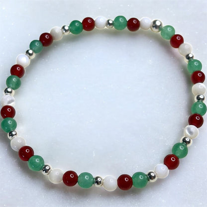 Beaded bracelet with red, green, and white beads on a light background.