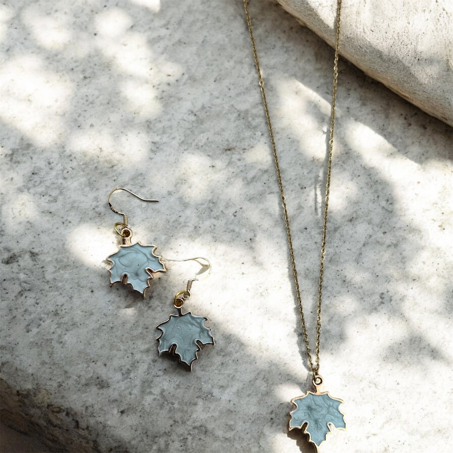Leaf-shaped jewelry set on a textured stone surface