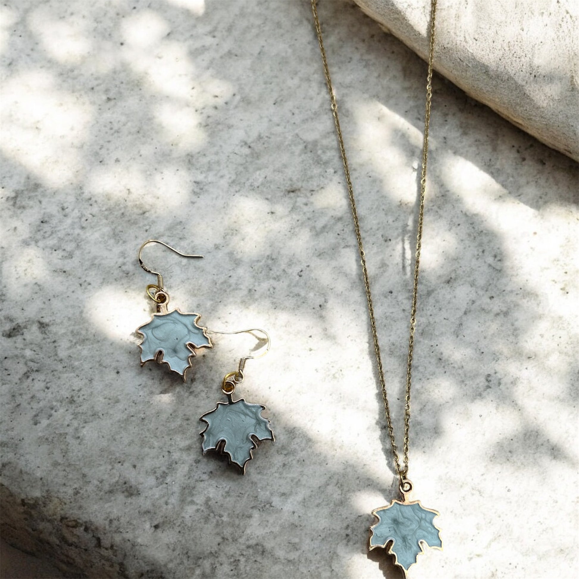 Leaf-shaped jewelry set on a textured stone surface