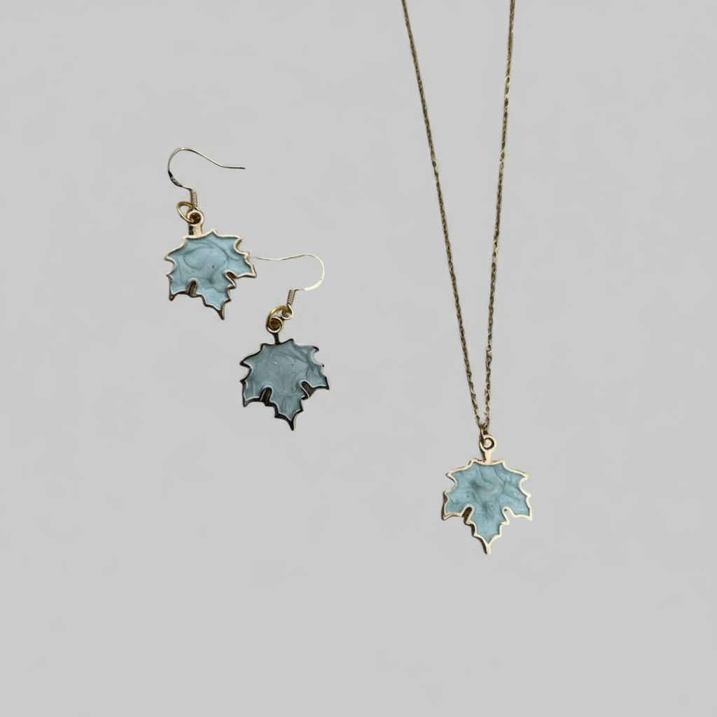 Jewellery set with leaf-shaped earrings and pendant on a grey background.