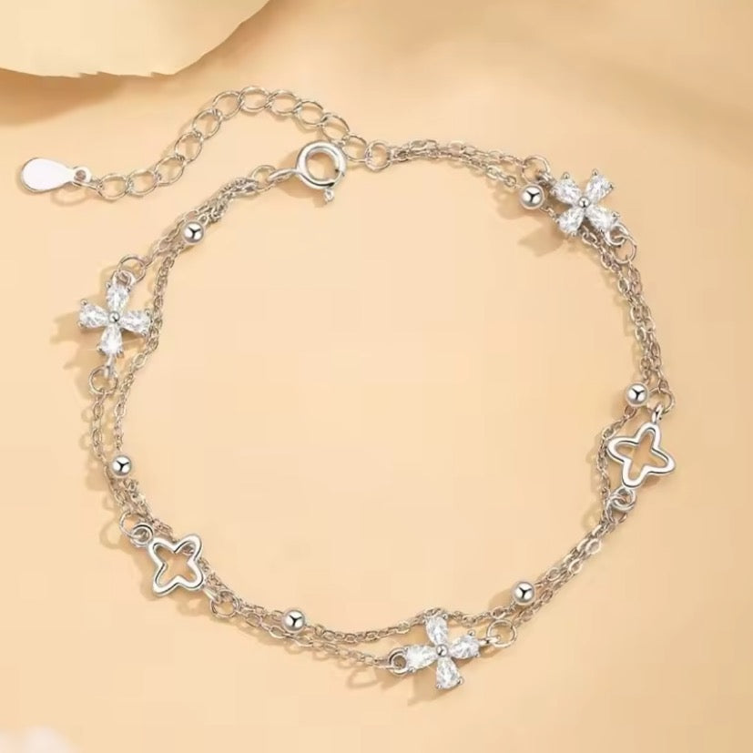 Silver bracelet with flower-shaped charms on a beige background