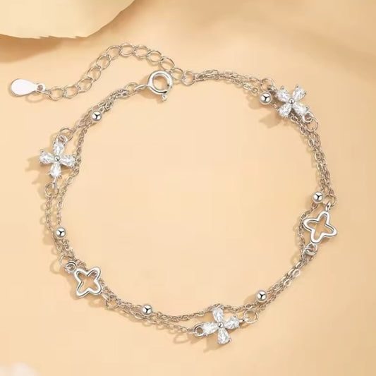 Silver bracelet with flower-shaped charms on a beige background