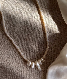 Delicate necklace with pearls on a textured fabric background.