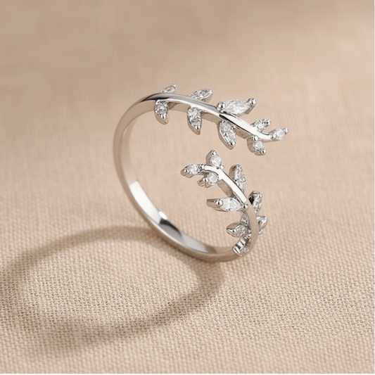Silver leaf-shaped ring on a beige fabric background