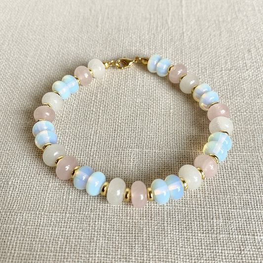 A multicolored bracelet with opalite, clear quartz, and rose quartz beads, featuring a gold-tone clasp.