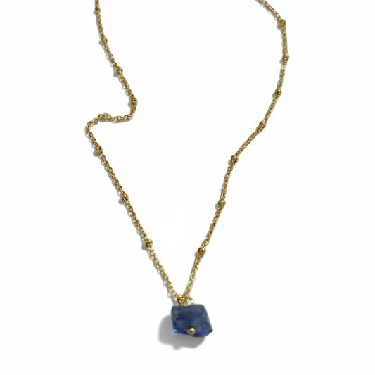 A gold-plated chain necklace with a single raw Tanzanite crystal pendant.